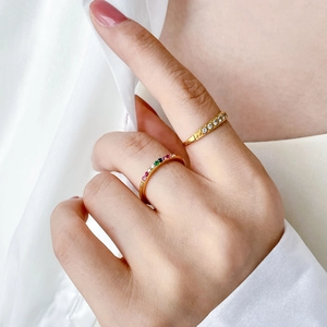 Close-up of dual gold stackable rings with rainbow zircons on a soft white fabric