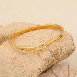 Elegante bracciale a testa di serpente dorato con cristalli su una superficie rocciosa