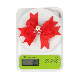 Detail view of a 3D red Christmas bow hair clip with Santa and lace on a scale