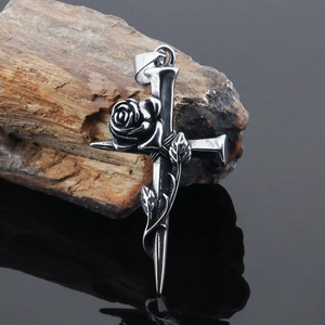 Detail of vintage stainless steel cross pendant with rose vines on rustic wood