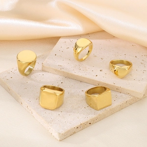 Détail d'un ensemble de bagues chevalières plaquées or 18 carats sur soie et travertin