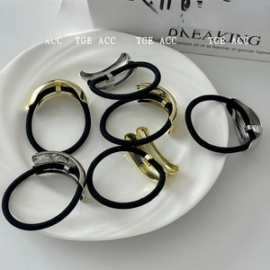 Detail of gold and silver curved metal hair ties with elastic bands on a white plate