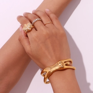 Close-up of a 18K gold plated body-shaped cuff bracelet and stacked rings on a model