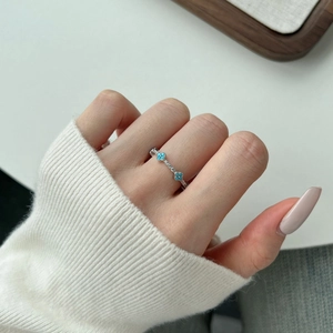 Close-up of a silver ring with light blue clover shapes and small white zircon stones