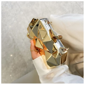 Detail of geometric acrylic clutch with gold and silver metallic mirrored facets and chain