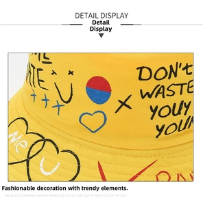 Detail of yellow canvas bucket hat featuring graffiti heart and letter print design