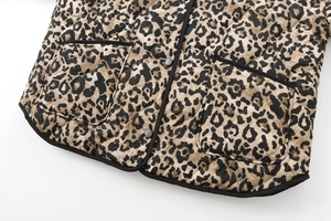Detail of leopard print quilted jacket showing hemline, pockets, and black piping trim