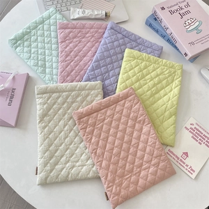 Detail of colorful quilted rhombic pattern padded laptop sleeves in soft pastel tones