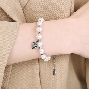 Detail of stainless steel bead bracelet with pearl accents and heart pendant on a blazer