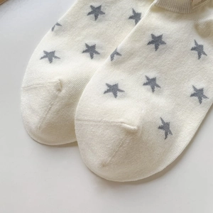Close-up of white knitted cotton sock featuring gray star patterns and reinforced toe seam