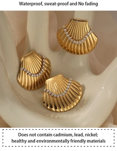 Detail of golden shell earrings with sparkling zircon inlay on a beige display
