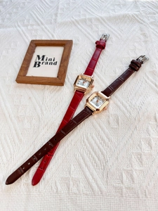 Detail view of vintage square watches with red and brown crocodile texture leather straps