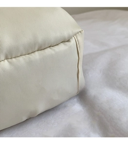 Detailed macro view of the cream nylon fabric texture and neat stitching on shell bag