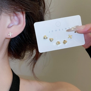 Set of three minimal gold stud earrings featuring heart, cross, and square designs