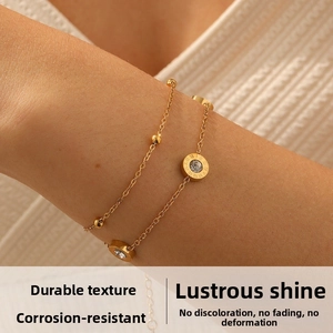 Détail du bracelet double chaîne dorée avec pendentif chiffres romains et cristal