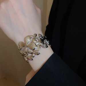 Détail de la manchette dorée à motifs floraux évidés et textures sur le poignet d'une femme