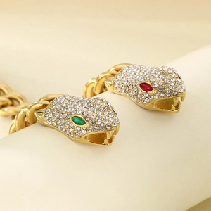 Close-up of golden Cuban chain bracelet with crystal snake head and colorful gem eyes