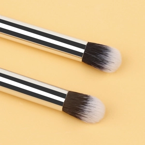 Detailed macro view of dual-ended makeup brushes with silver metal handles and soft fibers