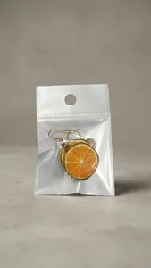 Detailed close-up of orange slice drop earrings featuring gold trim and vibrant finish