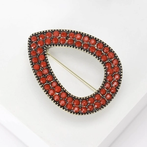 Detailed macro of antique gold teardrop brooch with inlaid red bohemian rhinestones
