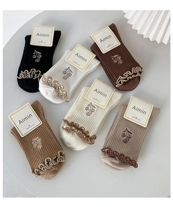 Detailed view of five pairs of cotton socks with floral embroidery and ruffled edges