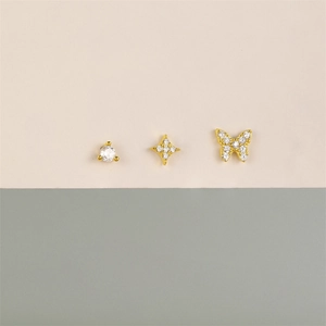 Detail of three gold star and butterfly earrings with sparkling cubic zirconia stones