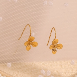 Macro shot of 18K gold plated floral hook earrings on soft lace textured background