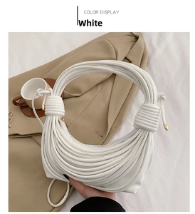 Detail of white knotted woven shoulder bag with metallic tips on a cozy background