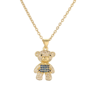 Golden teddy bear necklace with clear and blue crystals on a bright white background
