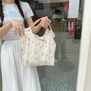 Detail of floral canvas tote bag with woven orange handles and magnetic closure