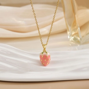 Detailed macro shot of a strawberry pendant necklace with pink enamel and gold chain