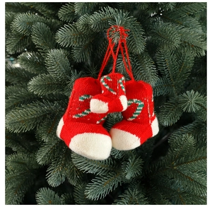 Close-up of red and white knitted Christmas stockings hanging on a green tree branch