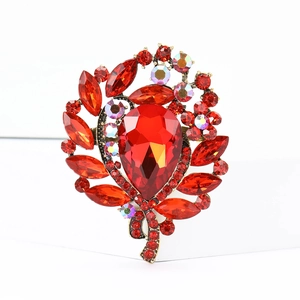Close-up of red leaf-shaped crystal brooch with sparkling rhinestones on golden base