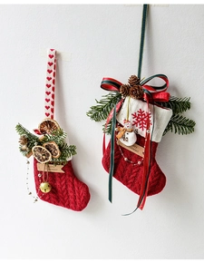 Detalle de calcetín navideño de punto rojo con muñeco de nieve, piñas y rodaja naranja