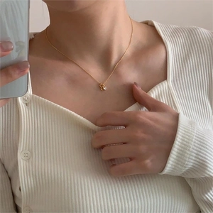 Close-up of a delicate gold heart lock and key pendant necklace on a model