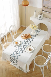 Detailed view of woven geometric diamond pattern with fringes on beige tablecloth