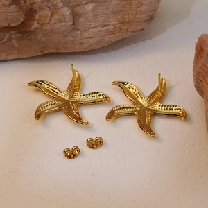 Macro shot of gold starfish earrings with realistic bionic texture on a natural stone base