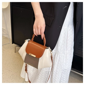 Detail of color-block PU leather handbag featuring metal buckle and adjustable strap