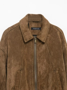 Detail of dark brown suede jacket collar with metallic zipper and textured fabric