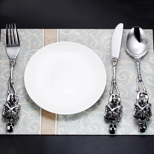 Gothic skull handled stainless steel cutlery set with knife fork and spoon on a white plate