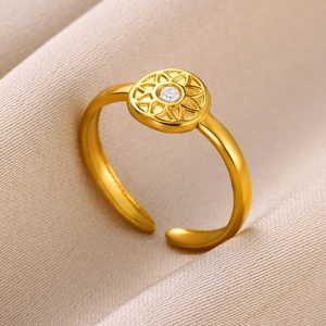 Close-up of golden adjustable ring with teardrop gem and sunburst pattern on silk