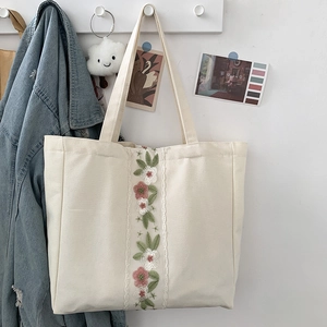 Dettaglio del ricamo floreale e del bordo in pizzo su una borsa tote in tela bianca