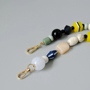Close-up of colorful handmade beaded chain with multi-shape beads and gold metal clasps