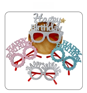 Close-up of four glittery Happy Birthday party glasses in silver, pink, blue, and white