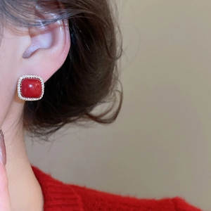 Close-up of vintage red zircon square stud earrings worn on ear with red sweater