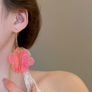 Gros plan de boucles d'oreilles fleurs en tulle rose avec détails en métal doré