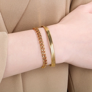 Wrist view of layered 18K gold-plated chunky Cuban and flat snake chain bracelet set
