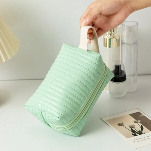 Dettaglio del beauty case in pelle PU trapuntata verde menta con manico color crema