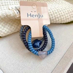 Close-up of spiral hair ties with heart and star pendants on a pink card