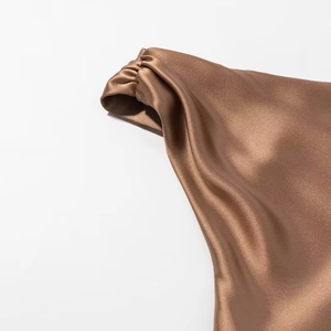 Detailed close-up of brown satin fabric showcasing elegant drapes and smooth silk texture